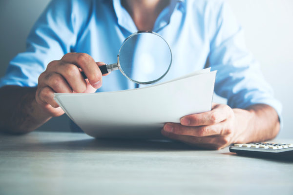 Photo d'une personne regardant une feuille blanche avec une loupe